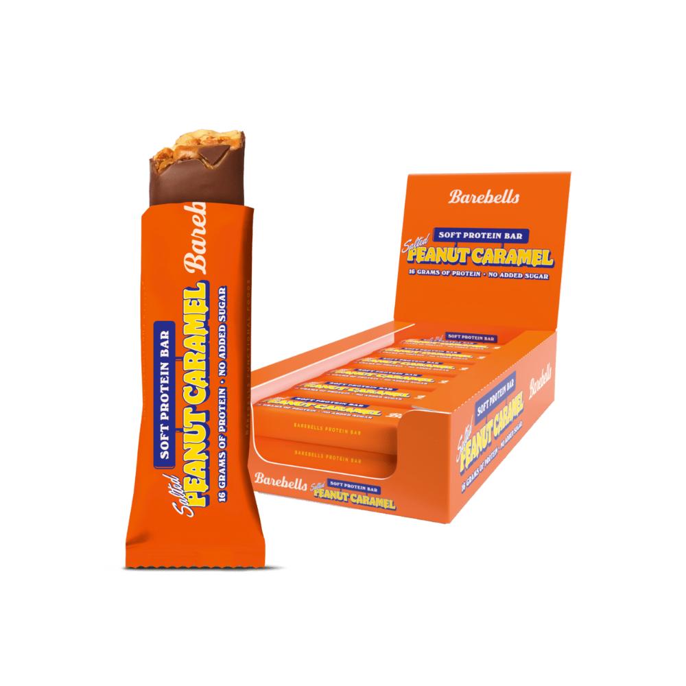 Barebells Salted Peanut Caramel Soft Bar, orange wrapper, with a bite taken, next to an open display box.