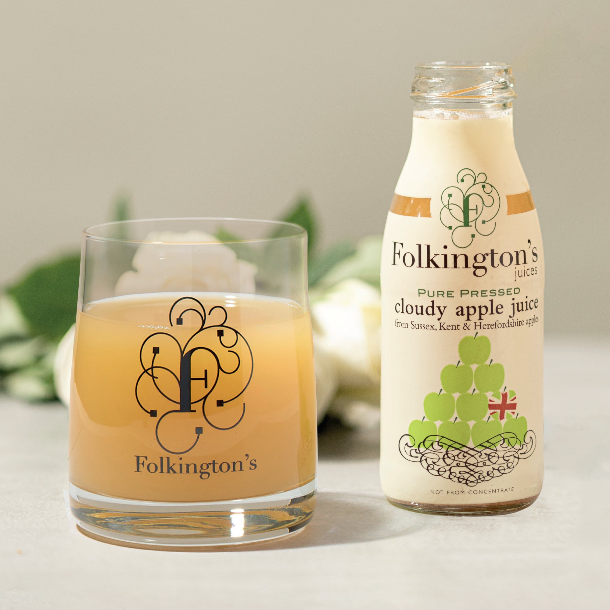 Folkington's Cloudy Apple Juice bottle and a glass filled with the juice, featuring the brand logo.