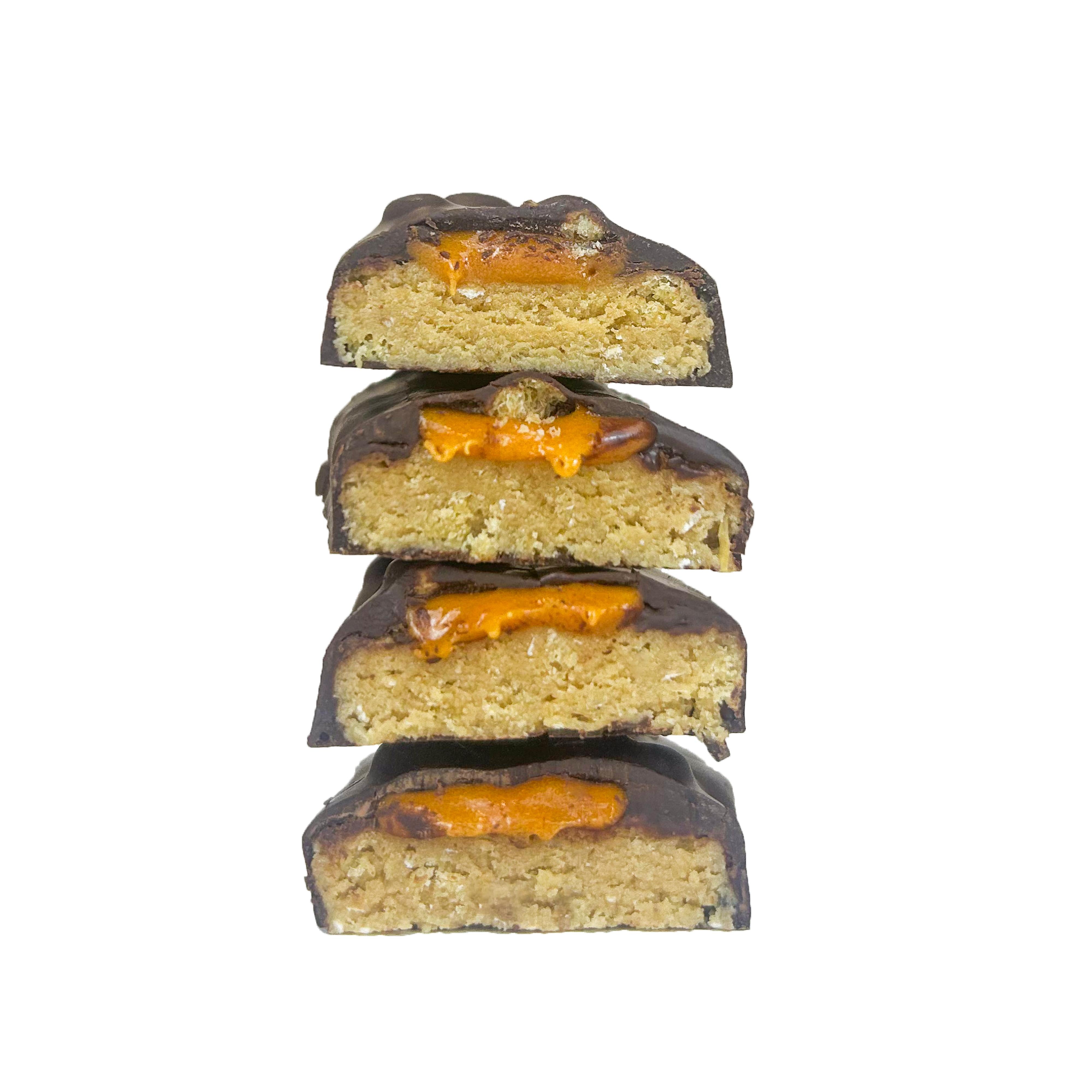 Four stacked YuBi Choc Orange protein bar halves, showing dark chocolate, orange caramel, and a light-colored base.