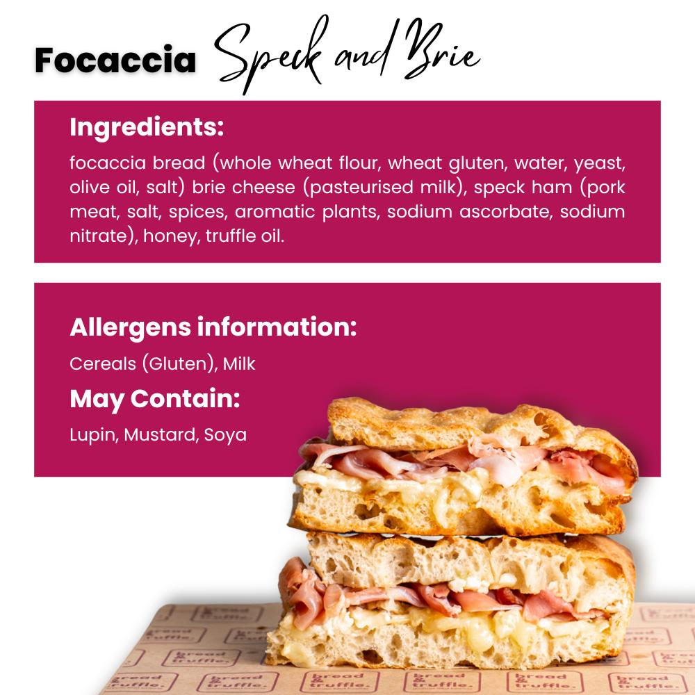 Golden focaccia sandwich with speck ham and creamy brie cheese, stacked on a branded paper.