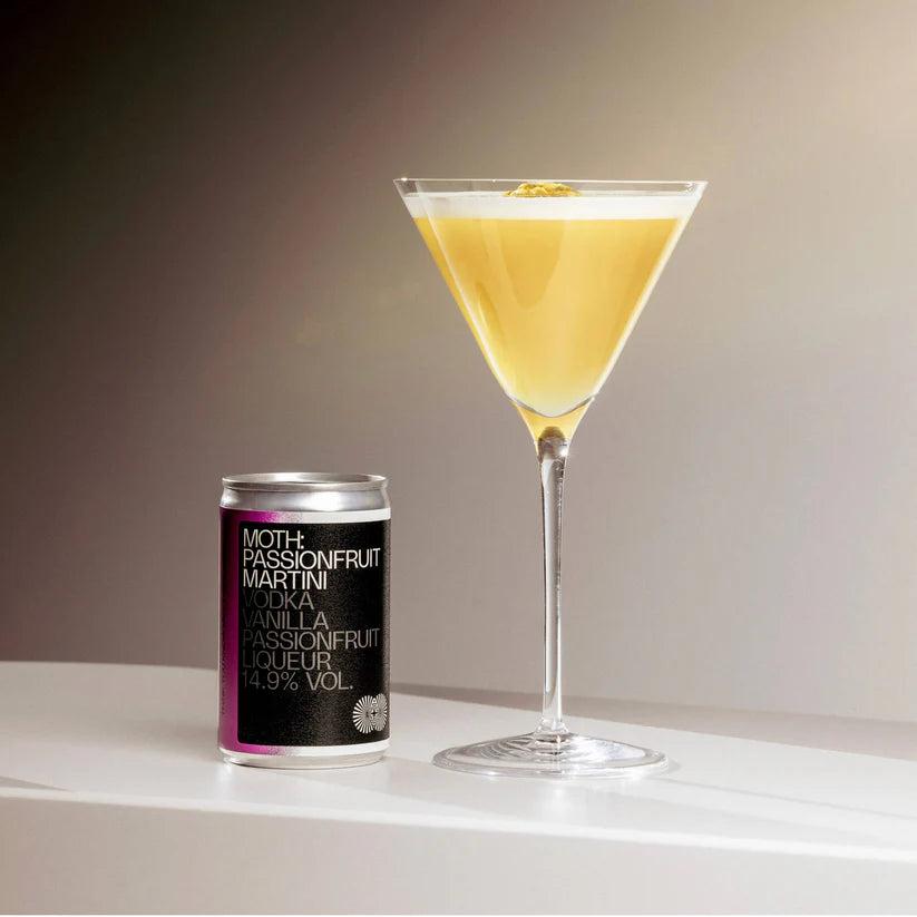 MOTH Passionfruit Martini can next to a martini glass with a yellow drink, foam, and garnish.
