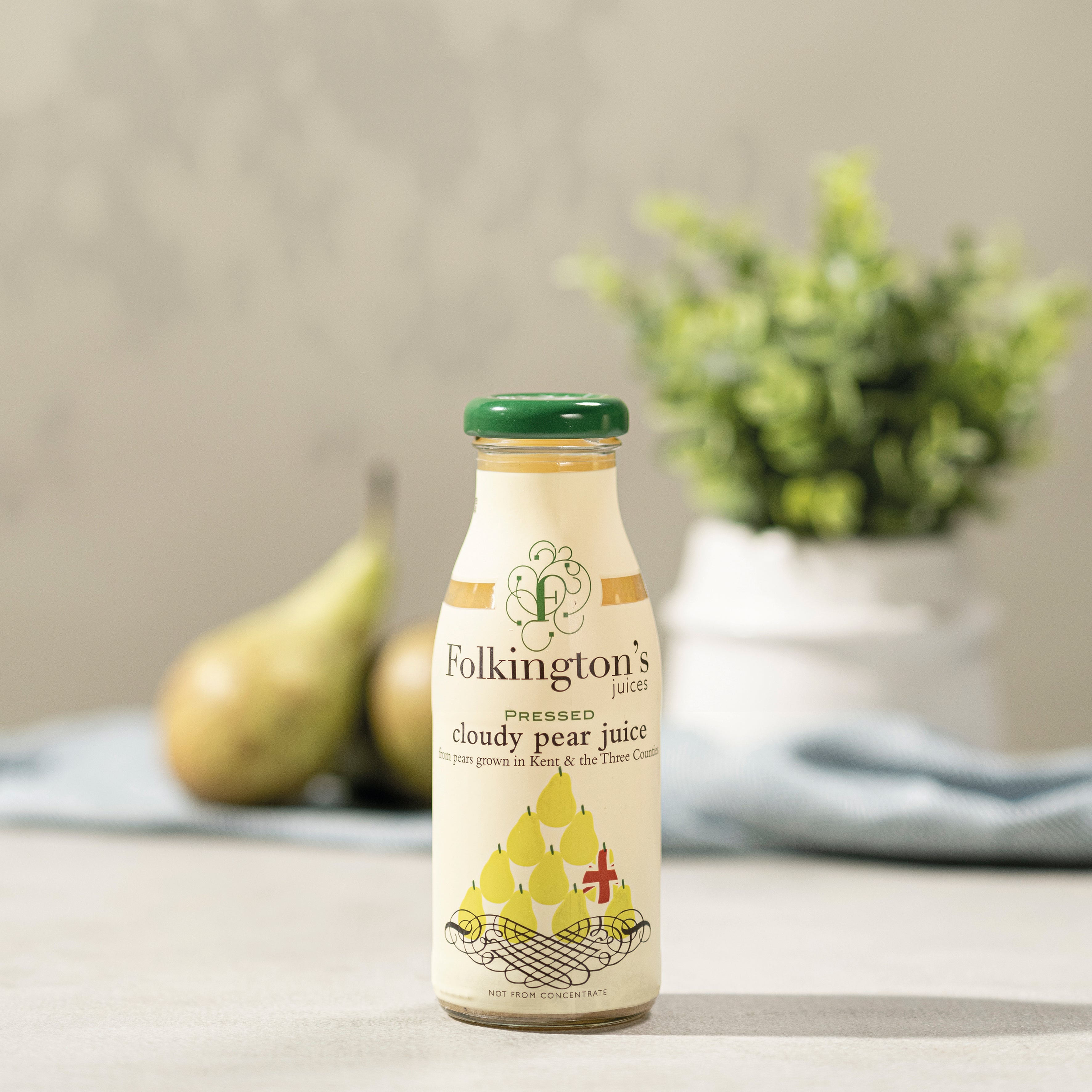 Folkington's Cloudy Pear Juice in a clear glass bottle with a green cap, featuring a pear illustration.