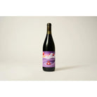 Dark red wine bottle with a vibrant purple label featuring an abstract landscape and red floating spheres.