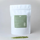 White Marna ceremonial grade matcha pouch with green label, beside a vibrant green matcha powder streak.
