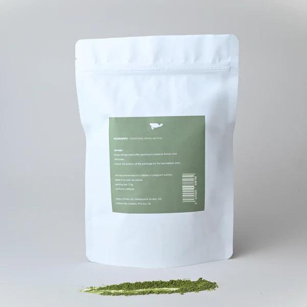 White Marna ceremonial grade matcha pouch with green label, beside a vibrant green matcha powder streak.