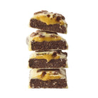 Stack of four YuBi Cookies & Cream protein bar halves with dark base, caramel layer, and white chocolate coating.