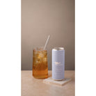 Marna Mango Iced Tea in a tall glass with ice and a straw, next to a light purple 330ml can.