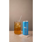 Marna Peach Iced Tea in a blue 330ml can next to a glass of iced tea with a straw.