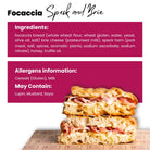 Golden focaccia sandwich with speck ham and creamy brie cheese, stacked on a branded paper.