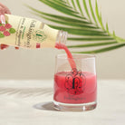 Folkington's Pressed Guava & Dragon Fruit Juice pouring into a branded glass, with a palm leaf background.