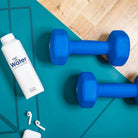 White Carton Water carton with sugarcane cap, next to blue dumbbells and white earbuds on a teal yoga mat.
