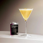 MOTH Passionfruit Martini can next to a martini glass with a yellow drink, foam, and garnish.
