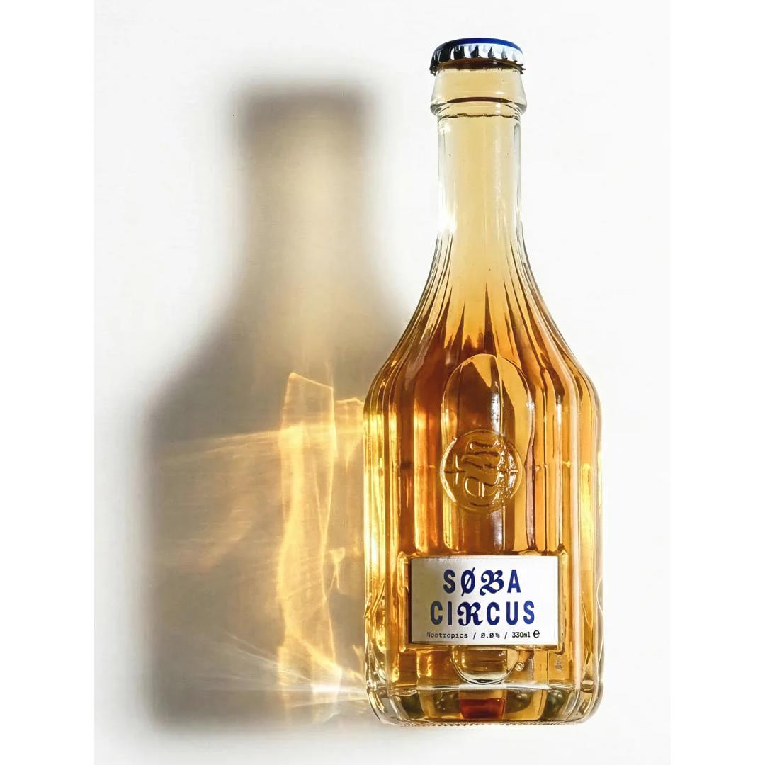 Soba Circus Sparkling Nootropic Drink in a clear, ribbed glass bottle with a blue cap and white label.