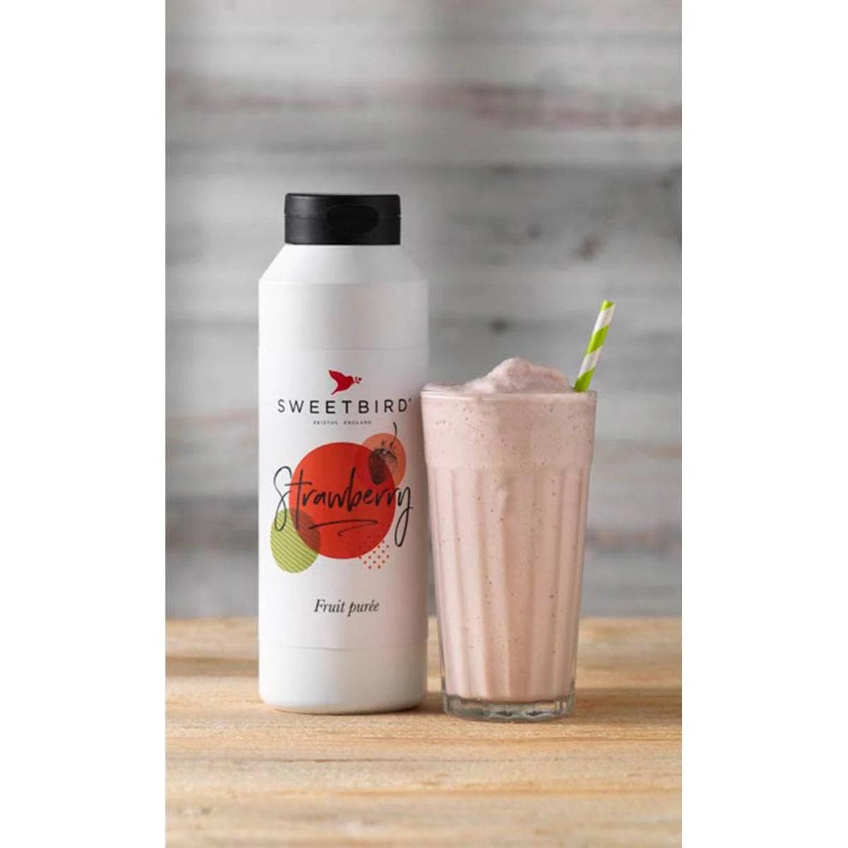 Sweetbird Strawberry Puree 1L white bottle with black cap next to a tall glass of pink strawberry milkshake.