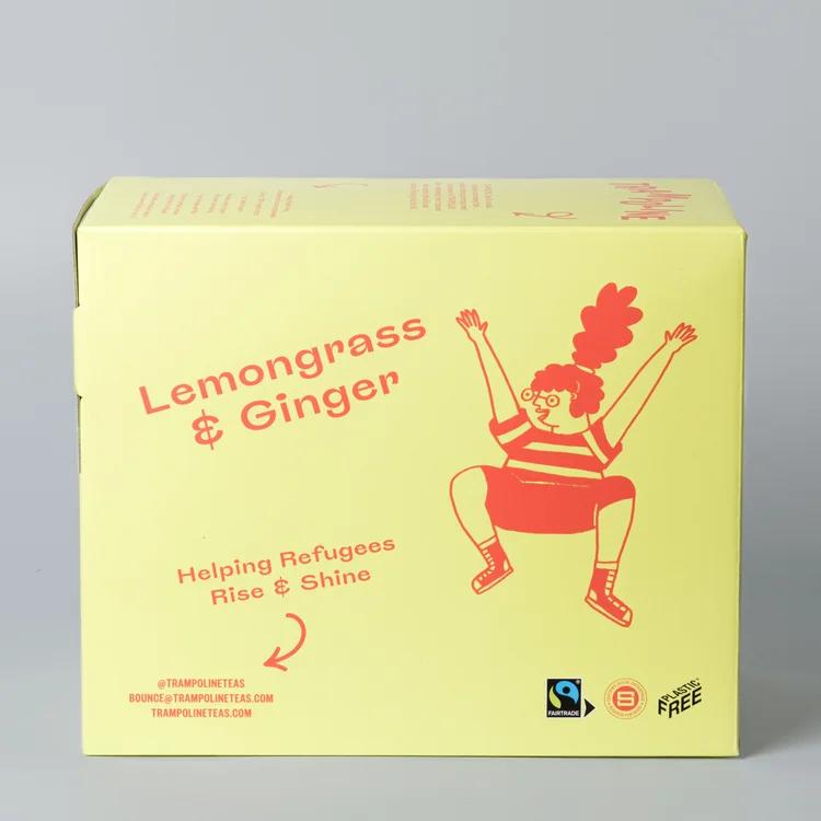 Yellow box of Trampoline Lemongrass & Ginger tea with a red cartoon figure, Fairtrade, and Plastic Free logos.