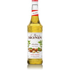 Monin Sugar Free Hazelnut Syrup 1L in a clear glass bottle with a red and white label, featuring hazelnuts and leaves.