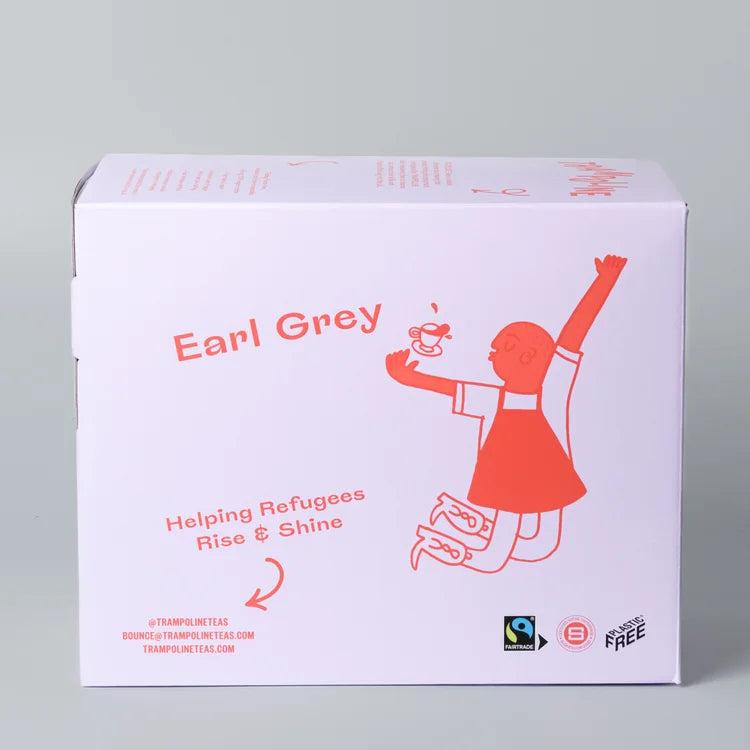 White box of Trampoline Earl Grey tea, featuring an orange line-art person jumping with a teacup, "Helping Refugees Rise & Shine" text, and Fairtrade logo.